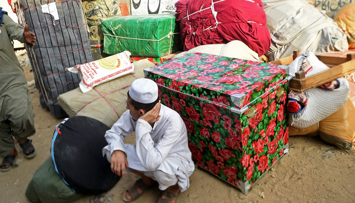 An Afghan refugee sits beside his belongings before loading them onto a bus at the Karachi bus terminal in Sindh province for his departure to Afghanistan on October 27, 2023. — AFP