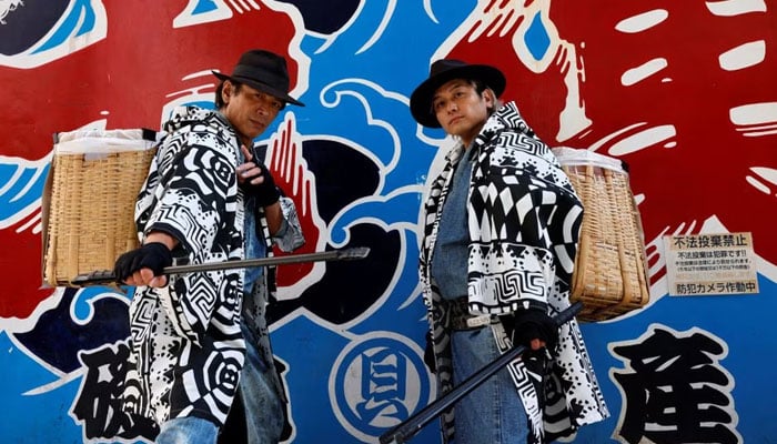 Keisuke Naka and Ikki Goto, members of Gomihiroi Samurai (trash-picking samurai) clad in denim yukata, poses for a photograph as they pick up trash on the street of Ikebukuro in the morning after Halloween in Tokyo, Japan November 1, 2023.—Reuters