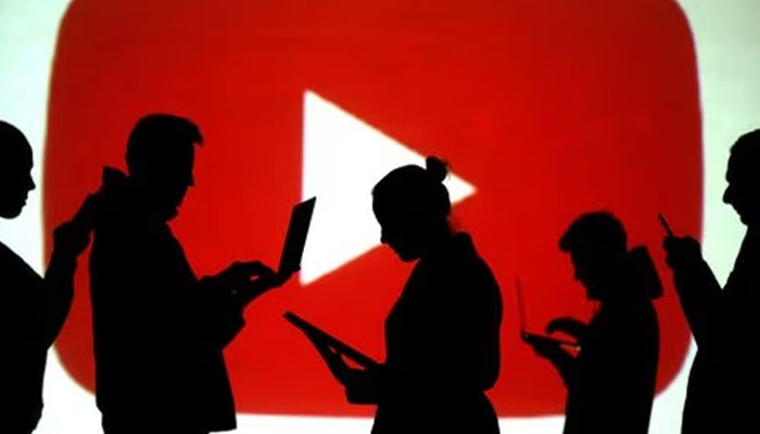 Silhouettes of laptop and mobile device users are seen next to a screen projection of the YouTube logo in this picture illustration taken March 28, 2018..—Reuters