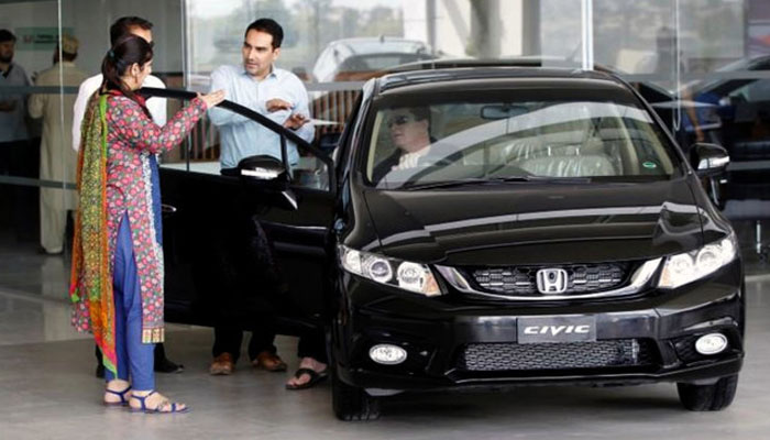 A customer speaks with salespeople at a car dealership in Rawalpindi, Pakistan. — Reuters/File