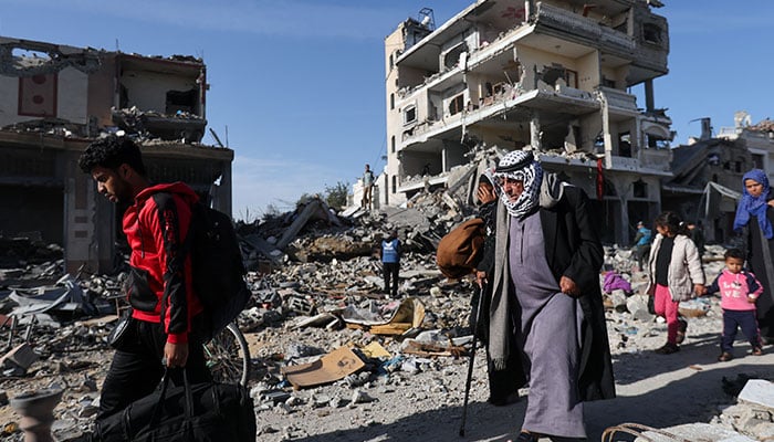 Displaced Palestinians return to their homes as they walk near houses destroyed in an Israeli strike during the conflict, amid the temporary truce between Hamas and Israel, in Khan Younis in the southern Gaza Strip on November 24, 2023. — AFP