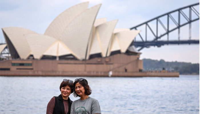 Chinese tourists take photographs in front of the Sydney Opera House and Harbour Bridge on September 27, 2023. — AFP