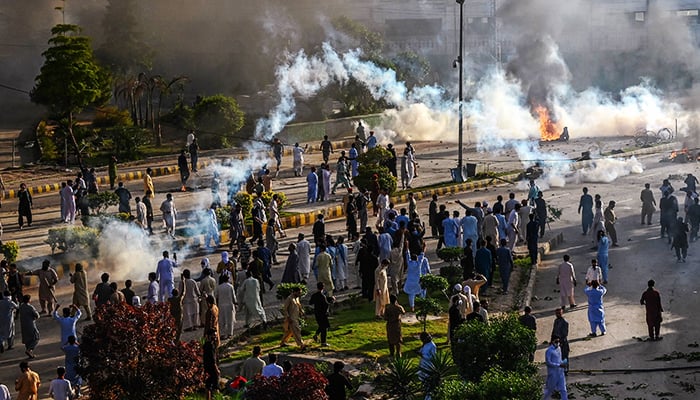 Police fire teargas shells towards PTI activists to disperse them during a protest against the arrest of Imran Khan in Peshawar on May 9, 2023. — AFP