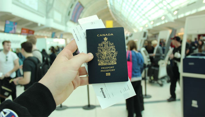 An individual holding a Canadian passport and boarding pass. — Unsplash