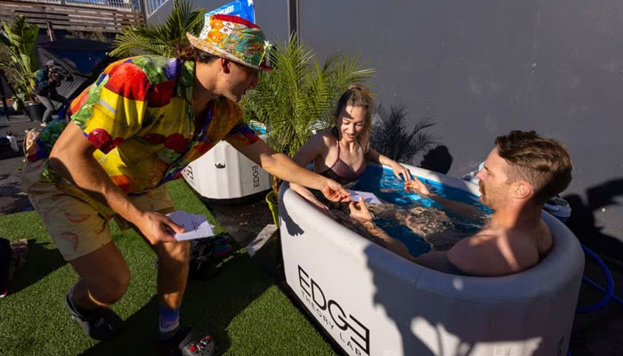 Michael Peck of Los Angeles (R) and Courtney Lakrois of San Francisco get question cards, as they attend their 3-minute speed date in an ice bath, in Santa Monica, California, US, December 16, 2023. —Reuters