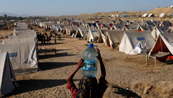 A displaced girl carries a bottle of water she filled from nearby stranded flood-waters, as her family takes refuge in a camp, in Sehwan, Pakistan, September 30, 2022. — Reuters