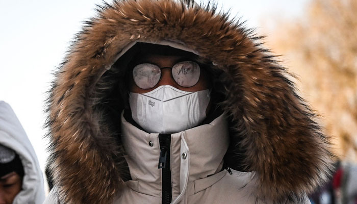 A man wearing fogged glasses walks along a street in Beijing on December 20, 2023. —AFP