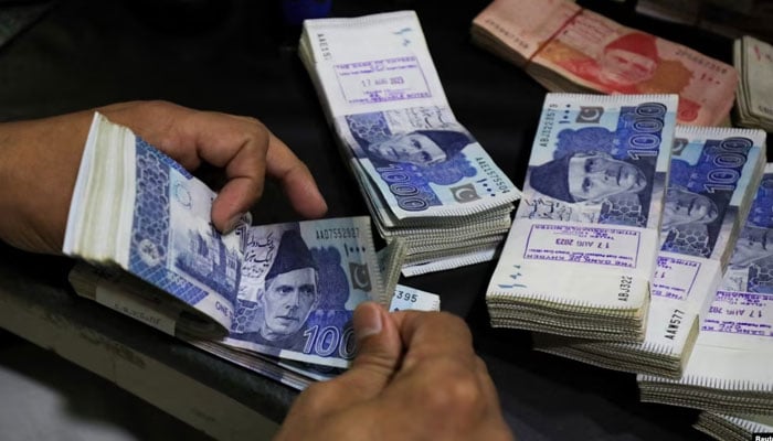 An employee counts Pakistani rupee notes at a bank in Peshawar, Pakistan, Aug. 22, 2023. — Reuters