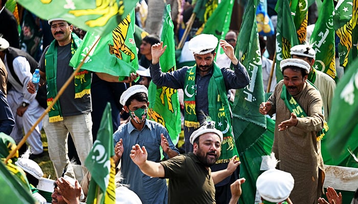 Supporters of former prime minister Nawaz Sharif wave the partys flags as they await his arrival at a park in Lahore on October 21, 2023. — AFP