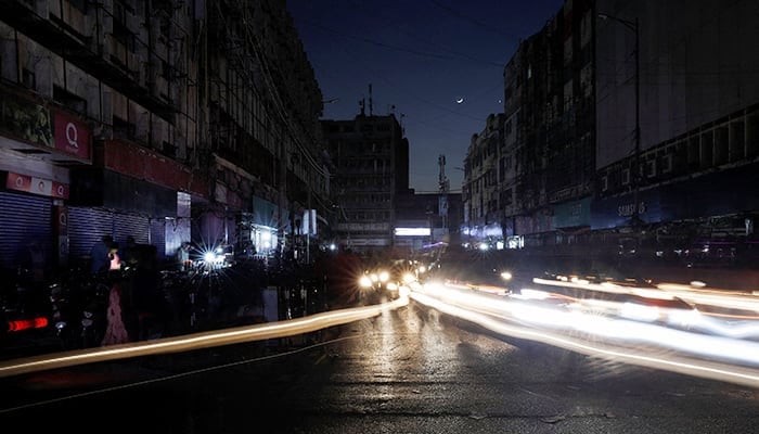 Vehicle lights cause light streaks on the road along a market, during a country-wide power breakdown in Karachi, Pakistan January 23, 2023. — Reuters