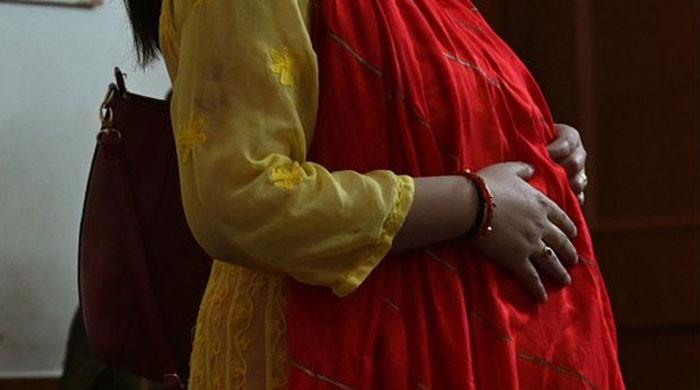 Indian young pregnant woman posing in a sari in the room, Mumbai