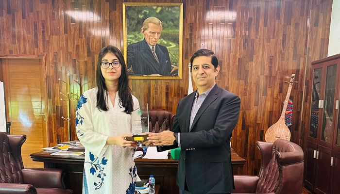 Climate and environmental activist Aneeqa Bashir (left) receives the award from Caretaker minister Arshad Wali Muhammad . — Supplied