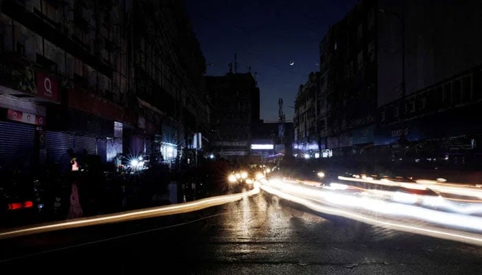 Vehicle lights cause light streaks on the road along a market, during a countrywide power breakdown in Karachi, on January 23, 2023. — Reuters