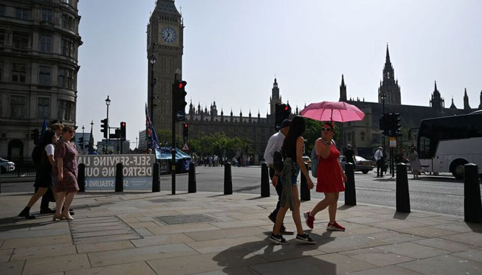 Pedestrians walk in the midday sun past the Palace of Westminster in central London, Sept. 6, 2023. — AFP