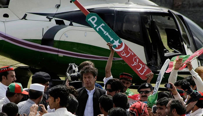 Behind former PTI chairman Imran Khan (C) a worker holds the symbol of PTI. — AFP/File