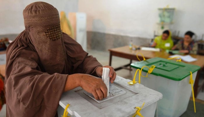 A burqa-clad woman casts her vote at a polling station in Peshawar on May 11, 2013. — AFP