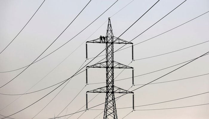 Technicians work to clean power transmission tower in Karachi, Pakistan, December 7, 2018. — Reuters