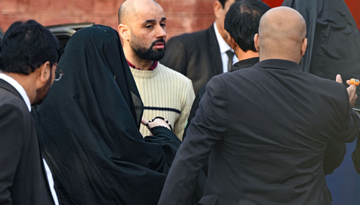 Security personnel escort Bushra Bibi, wife of jailed Imran Khan, as she arrives at Adiala Jail in Rawalpindi on December 12, 2023, before hearing of her husband at a special court. — AFP