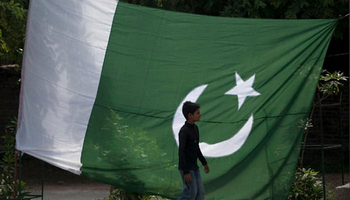 A child walks past the flag of Pakistan. — Reuters/File