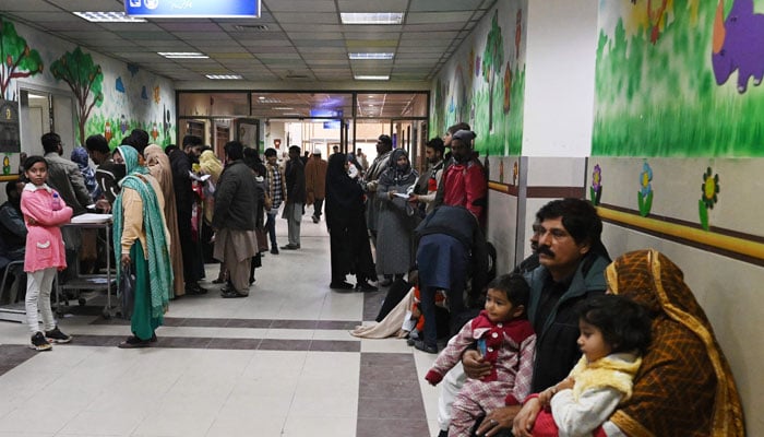 Parents wait with their child suffering from pneumonia, at the Childrens Hospital in Lahore on January 31, 2024. — AFP