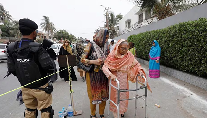 A voter walks next to a police officer as she prepares to cast her vote during the general election in Karachi, Pakistan, July 25, 2018. — Reuters