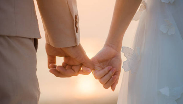 A married couple holding each others fingers. — iStock/File