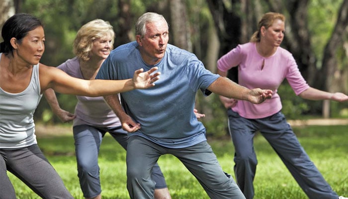 People perform tai chi in a park. — Harvard Health