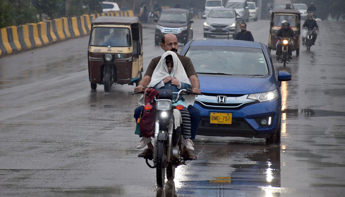 2 فروری 2024 کو کراچی میں بارش کے دوران مسافر سڑک پر جا رہے ہیں۔ — آن لائن