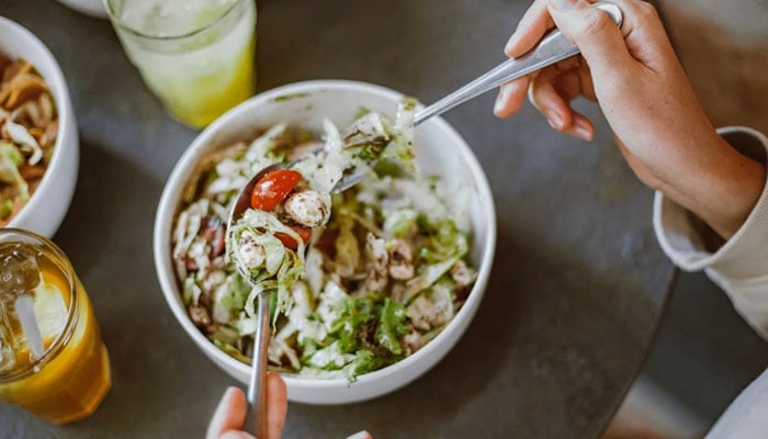 This image shows an individual holding a spoonful of salad. — Pexels