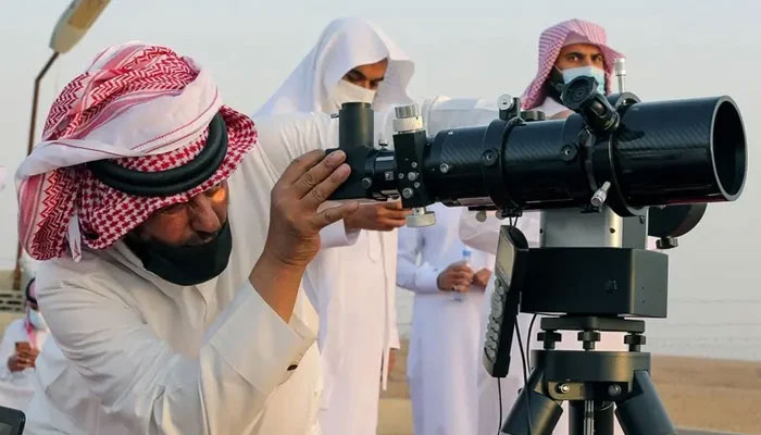 چاند دیکھنے والی کمیٹی کا ایک رکن 12 اپریل 2021 کو سعودی عرب کے شہر ریاض کے قریب رمضان المبارک سے پہلے چاند کو دیکھنے کے لیے دوربین کے ذریعے دیکھ رہا ہے۔