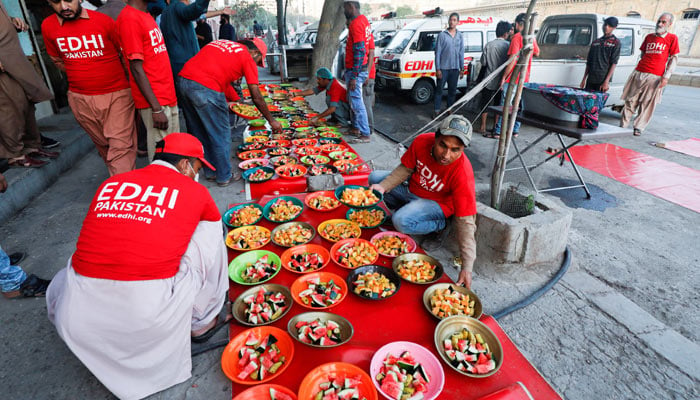 Volunteers of the Edhi Foundation, a non-profit social welfare programme, arrange food plates for the people to break their fast along a road in Karachi on April 3, 2023. — Reuters