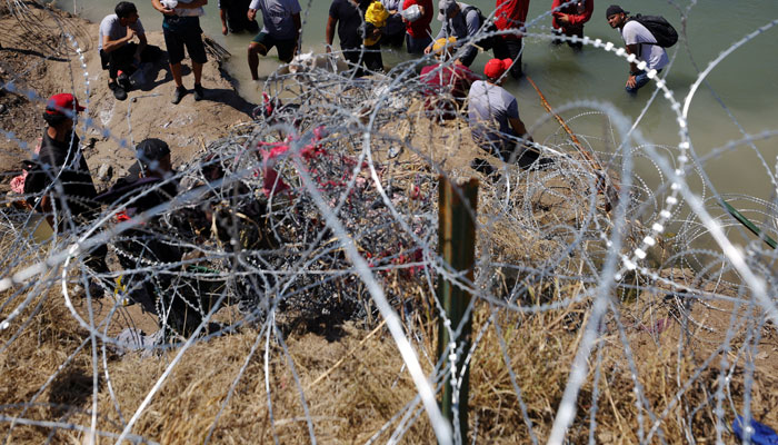 Migrants wait behind razor wire after crossing the Rio Grande into the United States in Eagle Pass, Texas, US, September 28, 2023. —Reuters