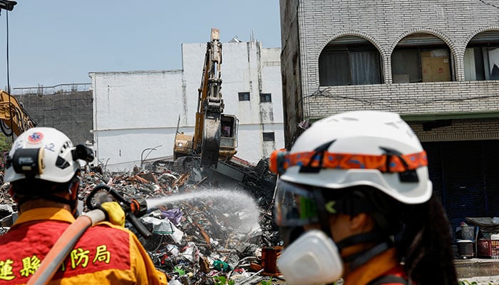 A worker carries out operations as a firefighter sprays water near them at the site where a building collapsed, following the earthquake, in Hualien, Taiwan on April 4, 2024. — Reuters