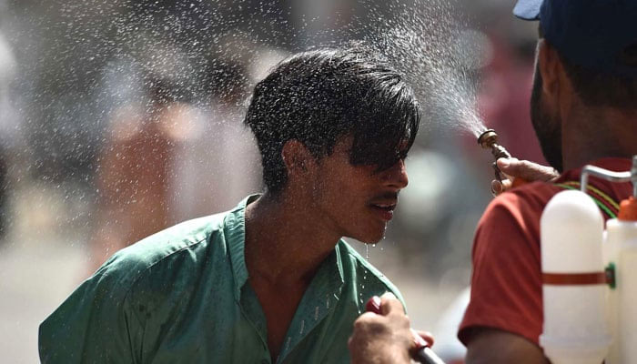 An Edhi volunteer sprinkling water on a bypassers face due to extreme heat wave. — INP/File