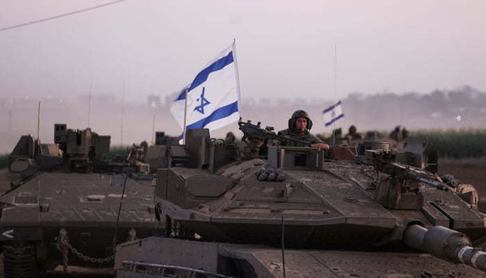 An Israeli soldier looks out from a tank as an artillery unit gathers on October 12, 2023. — Reuters
