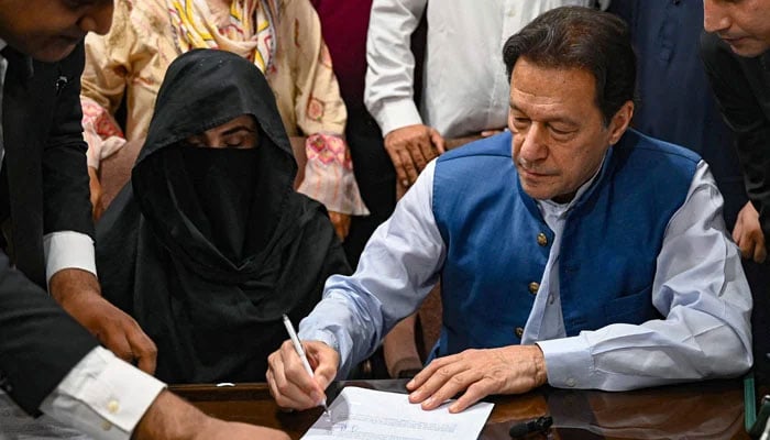 Pakistans former Prime Minister, Imran Khan (centre) along with his wife Bushra Bibi (centre, left) signs surety bonds for bail in various cases, at a registrars office in the Lahore High Court on July 17, 2023. — AFP