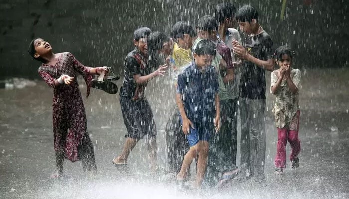 پاکستان میں تیز بارش کے دوران بچے سڑک پر کھیل رہے ہیں۔  - رائٹرز/فائل