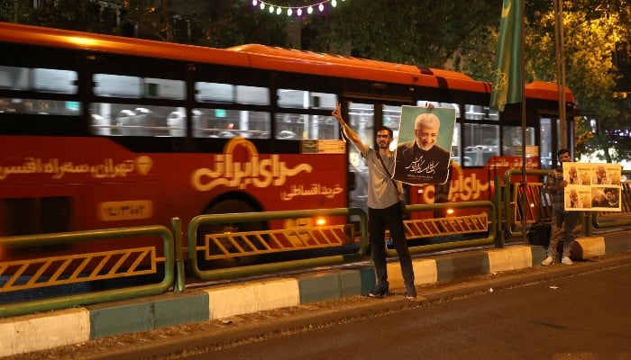 Supporters of Iranian presidential candidate Saeed Jalili hold posters of him on a street in Tehran, Iran, June 26, 2024. —Reuters
