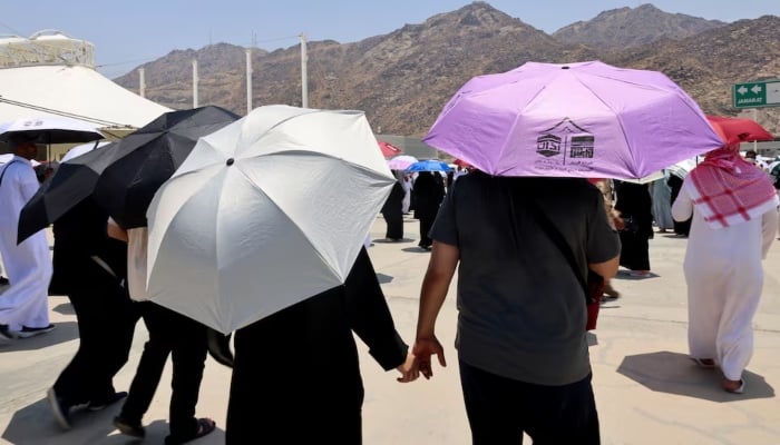 Muslim pilgrims hold hands as they walk with umbrellas during the annual Hajj pilgrimage in Mina, Saudi Arabia, on June 18, 2024. —Reuters