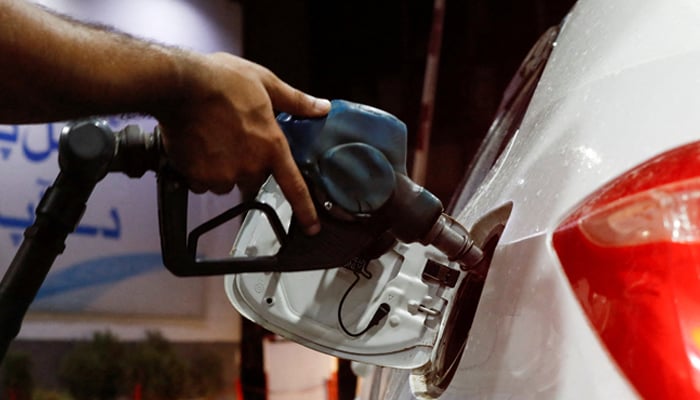 A worker holds a fuel nozzle to fills fuel in a car at petrol station in Karachi, on September 16, 2023. — Reuters