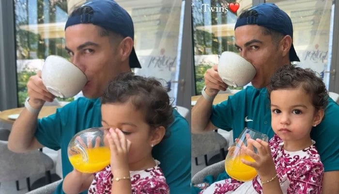 پرتگالی کھلاڑی کرسٹیانو رونالڈو چائے پی رہے ہیں جب ان کی بیٹی بیلا جوس پی رہی ہے۔  — Instagram/@georginagio