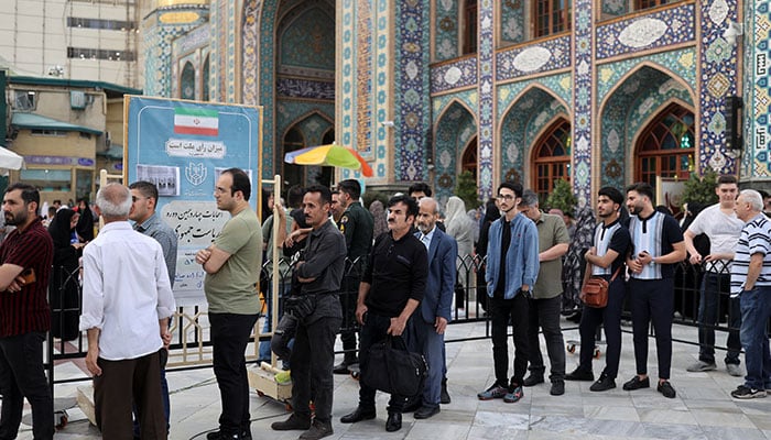ایرانی مرد 28 جون 2024 کو تہران، ایران میں ہیلی کاپٹر کے حادثے میں ہلاک ہونے کے بعد ابراہیم رئیسی کے جانشین کا انتخاب کرنے کے لیے قبل از وقت صدارتی انتخابات میں پولنگ اسٹیشن پر ووٹ ڈالنے کے لیے قطار میں کھڑے ہیں۔ - رائٹرز