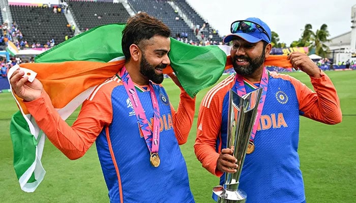 بھارت کے ویرات کوہلی (L) اور کپتان روہت شرما 29 جون، 2024 کو برج ٹاؤن، بارباڈوس میں کینسنگٹن اوول میں بھارت اور جنوبی افریقہ کے درمیان ICC مردوں کے T20 ورلڈ کپ 2024 کا فائنل کرکٹ میچ جیتنے کے بعد ٹرافی کے ساتھ جشن منا رہے ہیں۔ — اے ایف پی