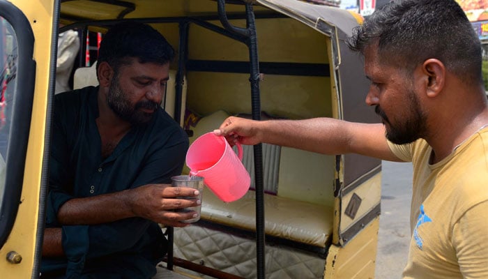 Commuters quench their thirst by chilled juice to beat the heat at a relief camp of heatstroke at Shahrah-e-Faisal road in Karachi on June 26, 2024. — APP