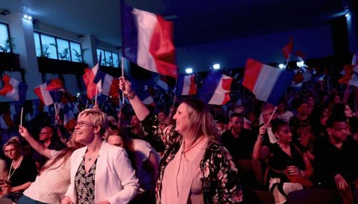 Supporters of Marine Le Pen, French far-right leader and far-right Rassemblement National (National Rally - RN) party candidate, hold French flags at the venue for Marine Le Pens reaction speech before partial results in the first round of the early French parliamentary elections, in Henin-Beaumont, France, on Sunday. — Reuters