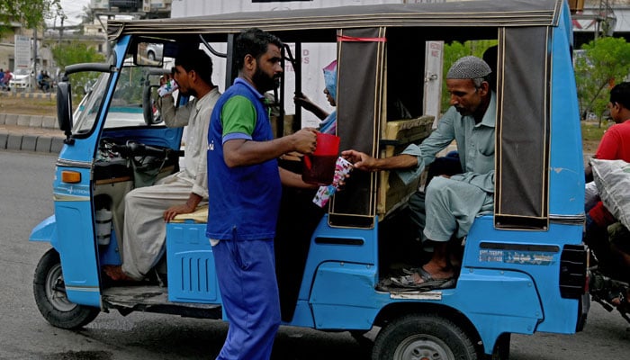 A man serves cold drinks to commuters along a street on a hot summer day in Karachi on June 27, 2024. — AFP