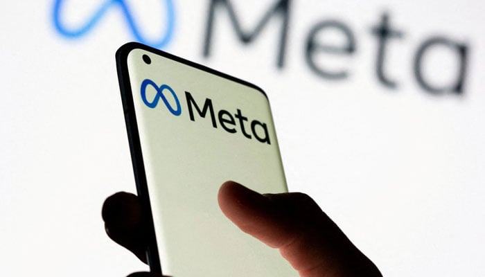 A woman holds a smartphone with the Meta logo in front of a display of Facebooks new rebranded logo Meta in this illustration picture taken on October. 28, 2021. — Reuters