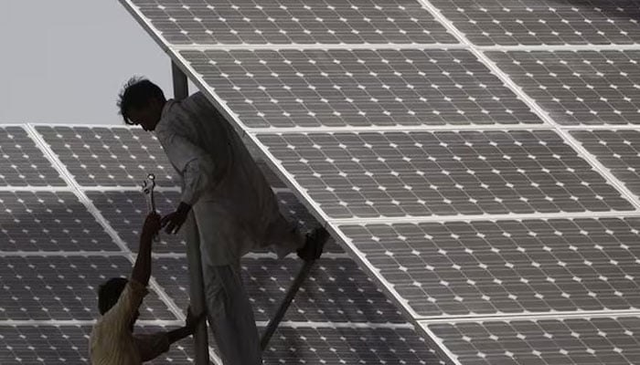 Technicians work on a solar panel at a power station about 25 km from Karachi June 18, 2010. — Reuters
