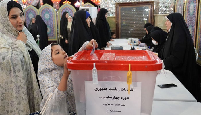 An Iranian woman casts her vote with her daughte, at the a Muslim Shiite shrine being used as a polling station, in Tehran on July 5, 2024. — AFP