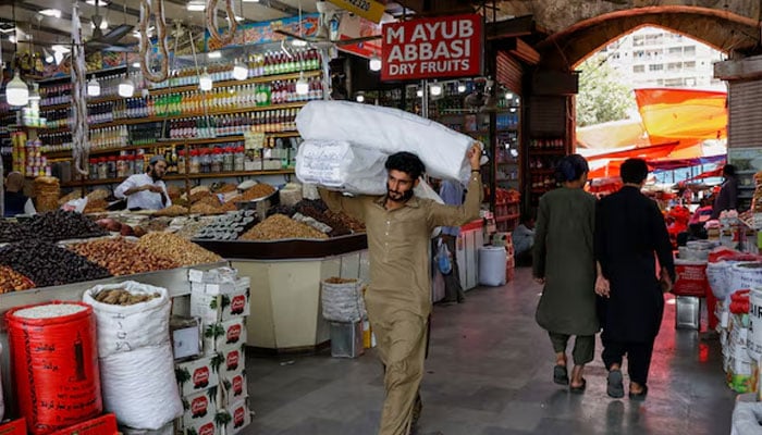 A man walks with sacks of supplies on his shoulder to deliver to a nearby shop at a market in Karachi, Pakistan June 11, 2024. — Reuters